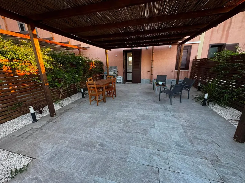 La terrazza coperta dal pergolato, col tavolo da pranzo in legno e il salottino da esterno